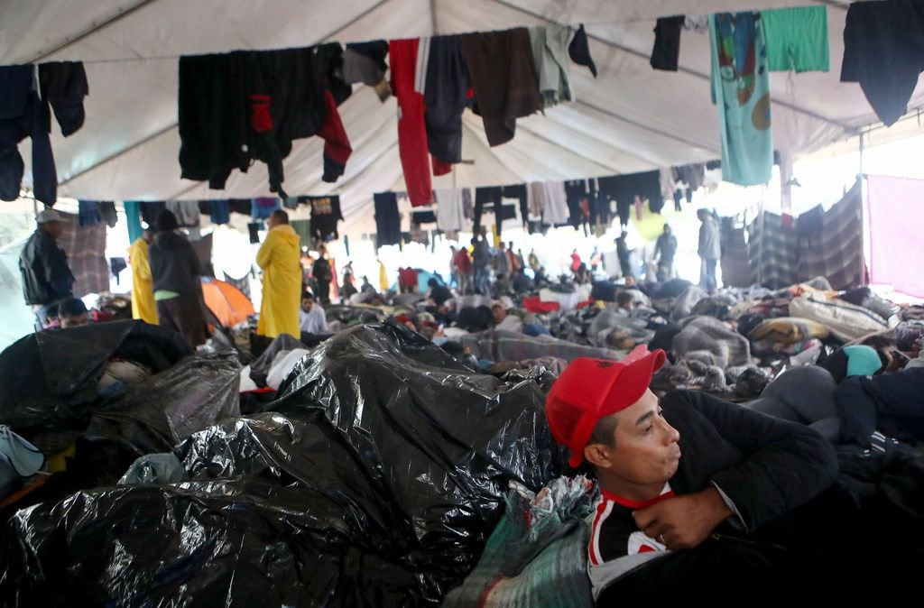 Migrants rested under a tent Thursday in a temporary shelter set up for migrants in Tijuana,...