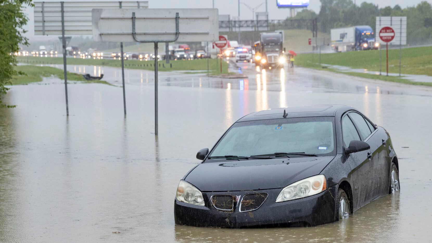 A stalled car sits abandoned on the flooded Interstate 635 Service Road on Monday, Aug. 22,...