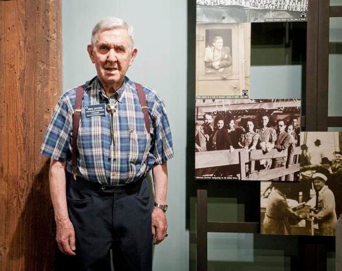 
Mike Jacobs poses next to a photo of himself in an exhibit at the Dallas Holocaust...