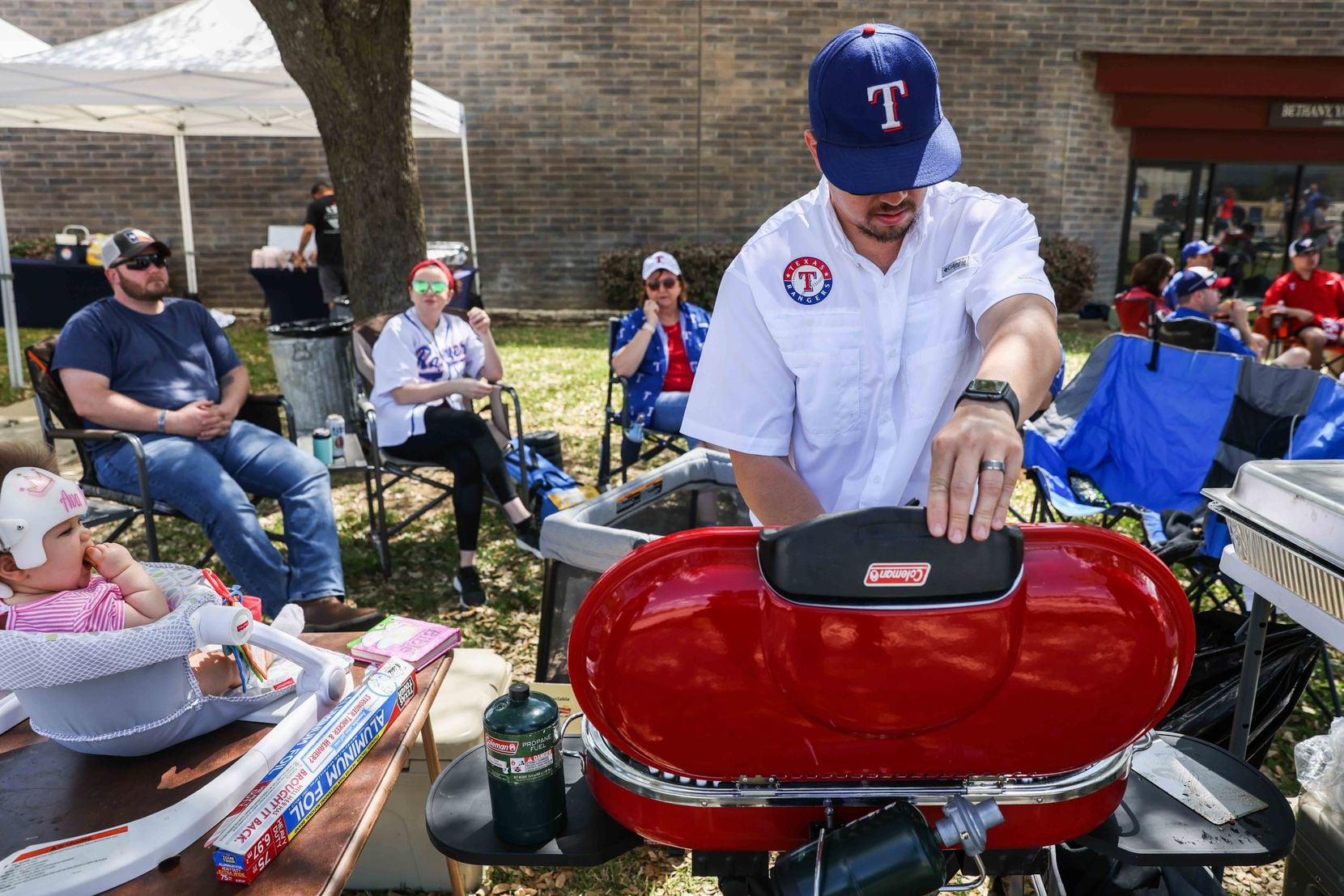 Sean Smith next to his daughter Ava Smith cooks some burgers outside the Globe Life Field in Arlington, Texas on Monday, April 5, 2021,  before the game between Texas Rangers and Toronto Blue Jays on opening day. (Lola Gomez/The Dallas Morning News)