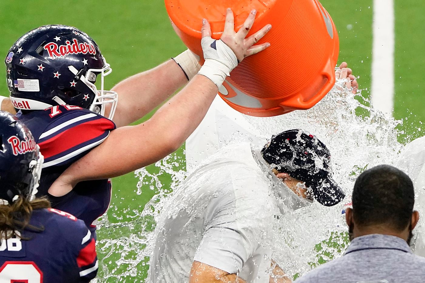 Denton Ryan head coach Dave Henigan is doused with water by offensive lineman Henry Appleton (72) in celebration of a 59-14 victory over Cedar Park to win the Class 5A Division I state football championship game at AT&T Stadium on Friday, Jan. 15, 2021, in Arlington, Texas. (Smiley N. Pool/The Dallas Morning News)
