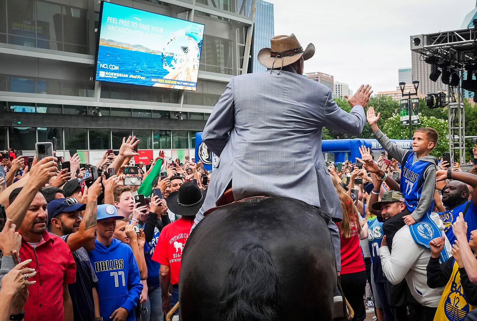 Charles Barkley high fives a young fan as he arrives on horseback at the American Airlines...