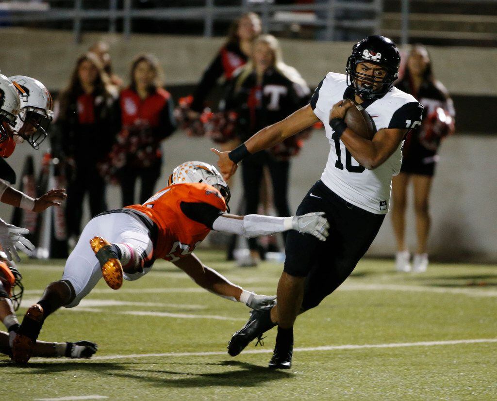 Euless Trinity's Valentino Foni (16( gets away from a tackle by Haltom's Gavon Lange (24) to...