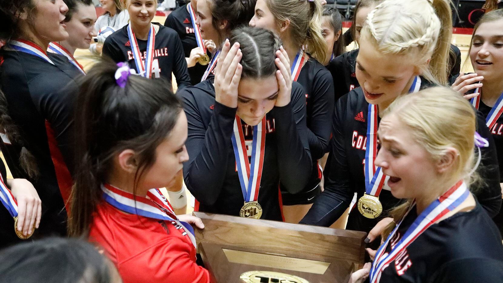 The Colleyville Heritage High School volleyball team looks over their state trophy after...