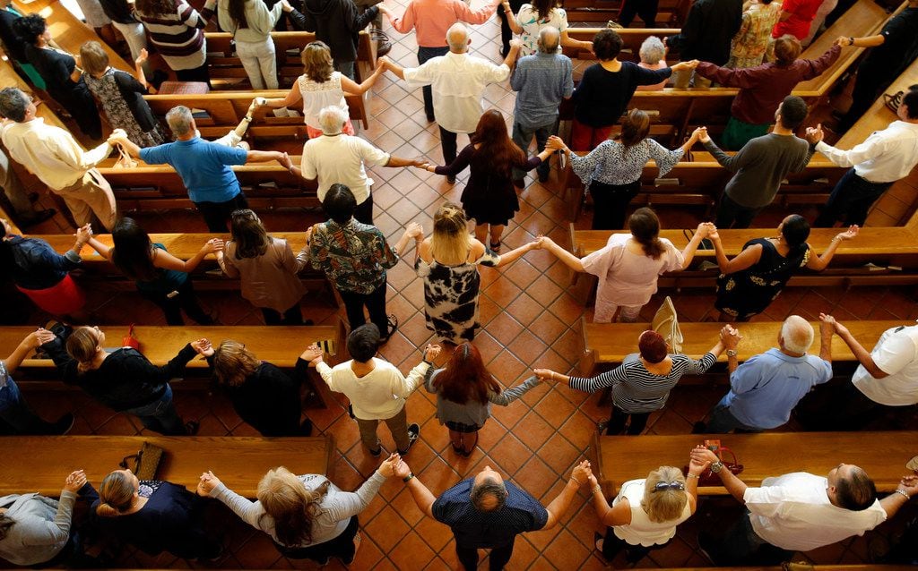 Congregation held hands as they sang during a morning service at St. Pius X Church in El...