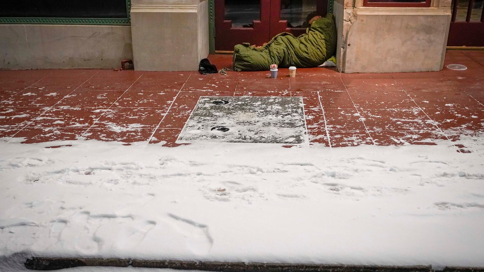 With temperatures in the single digits, a homeless person sleeps in the doorway of Dallas' Majestic Theater during a brutal winter storm on Feb. 14, 2021.