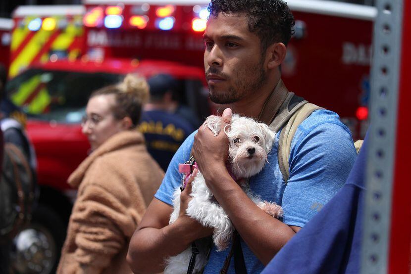 Isaiah Allen, a resident of the damaged apartments, holds onto a dog, Princess, as he...