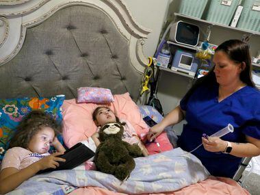 Lincoln Brooks (left), 4, watches a show with older sister Charlotte Brooks, 5, while Cora...