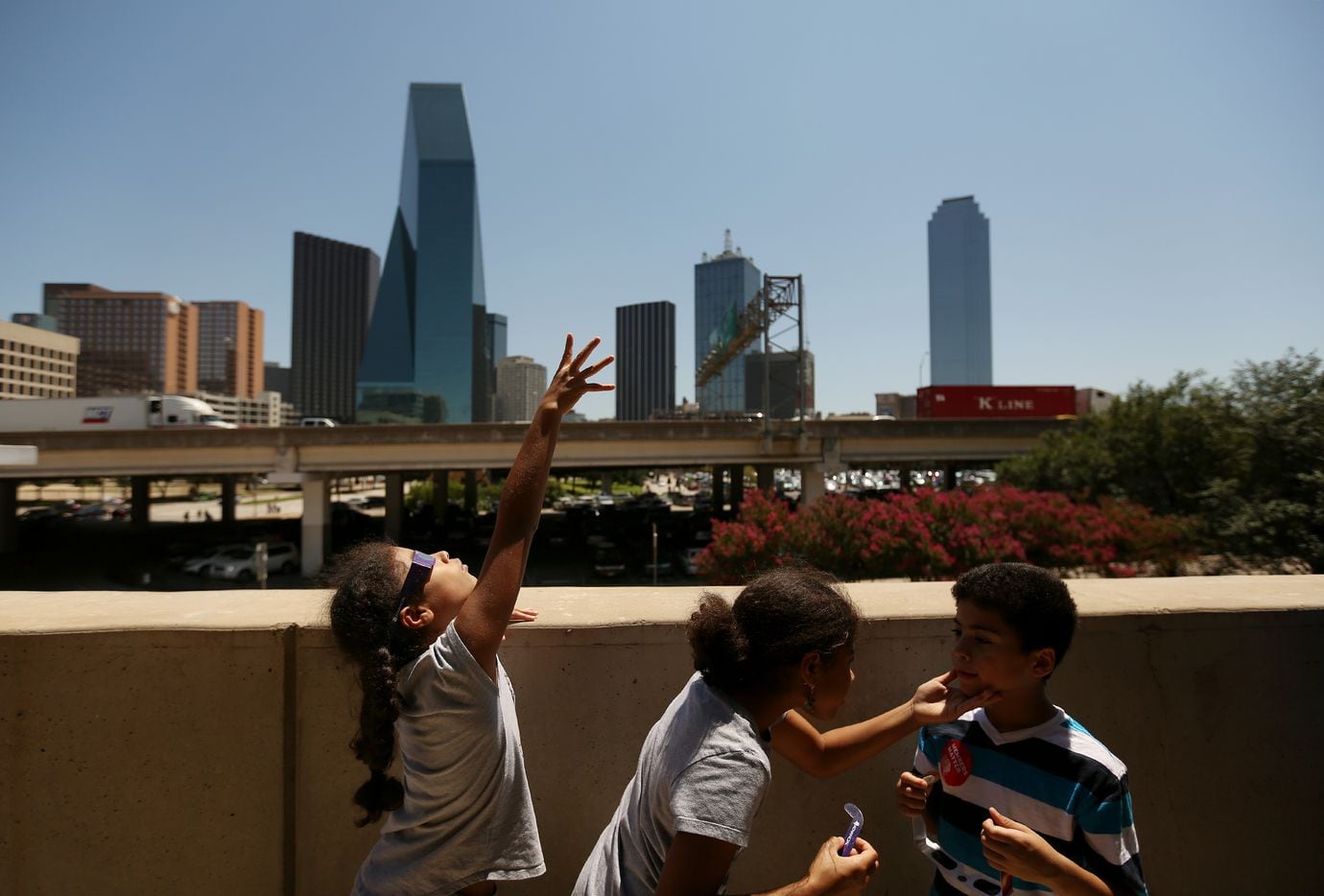 Iliana Harris, 10, of Dallas, reaches for the sky during a solar eclipse outdoor watch party at the Perot Museum of Nature and Science.