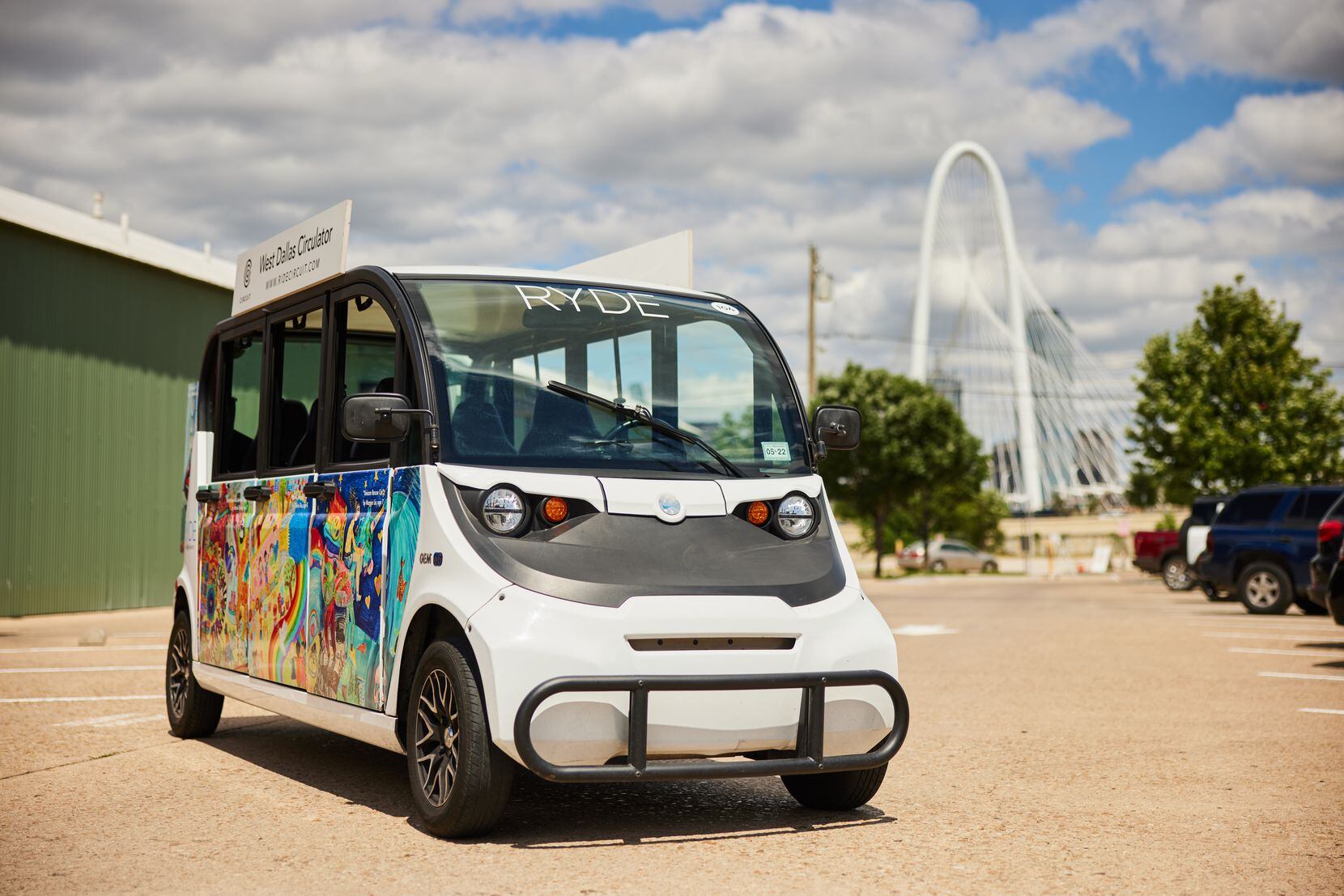White six-door electric shuttle with colorful advertising on the side and and Dallas in the...