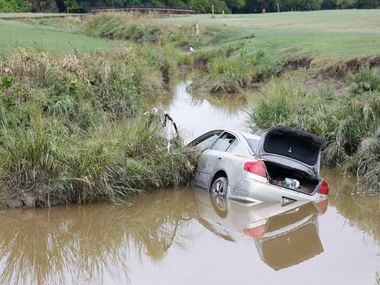 A stranded car remains on a creek at Paschall Park in Mesquite, day after Dallas-Fort Worth...