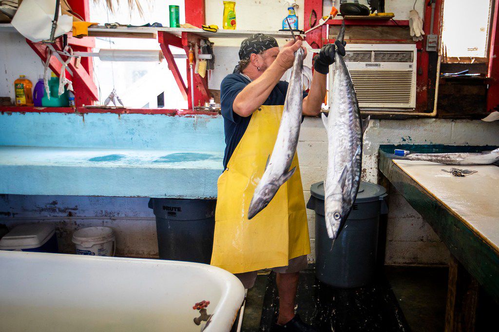 Tim Thompson cleans fish at Fisherman's Wharf in the Texas Gulf Coast city of Port Aransas,...