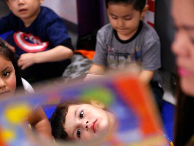 Pre-K student Ibarra Isaias (center) listens to his teacher Ana Perez Garcia read from the...