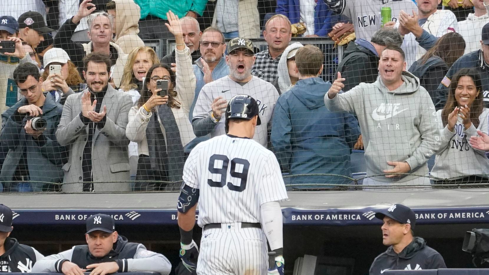 Fans cheer New York Yankees' Aaron Judge walks to the dugout after striking out in the...