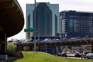 Traffic traverses the elevated I-345 overhead as other vehicles travel on North Cesar Chavez...