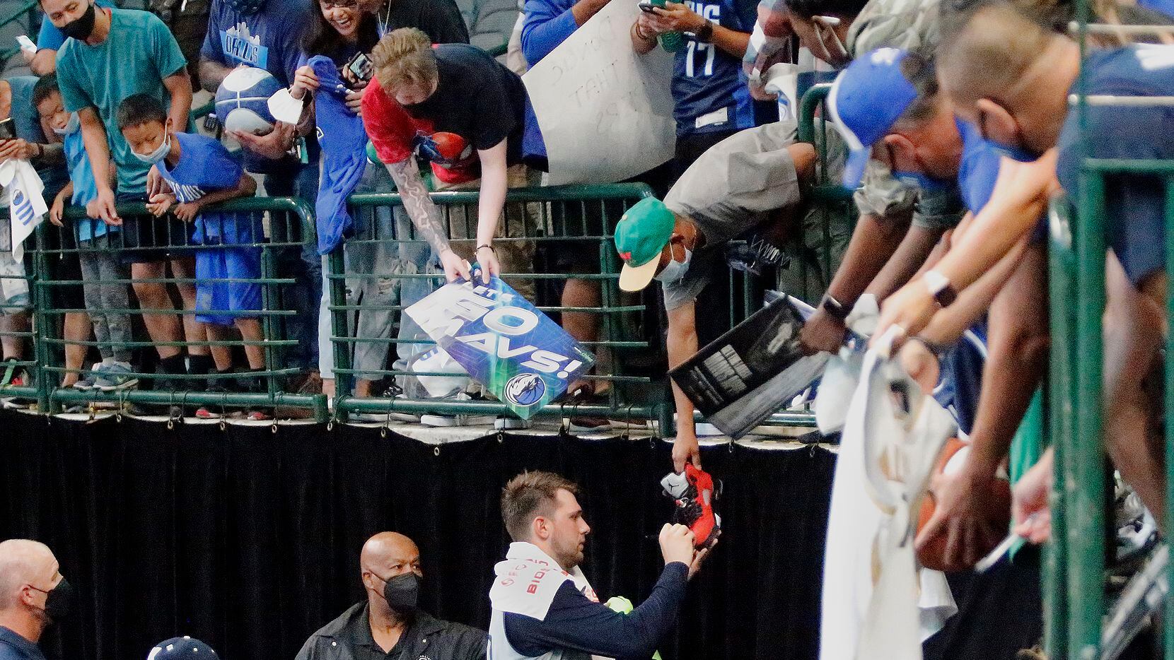 Dallas Mavericks guard Luka Doncic (77) autographs a shoe for one of the fans after the...