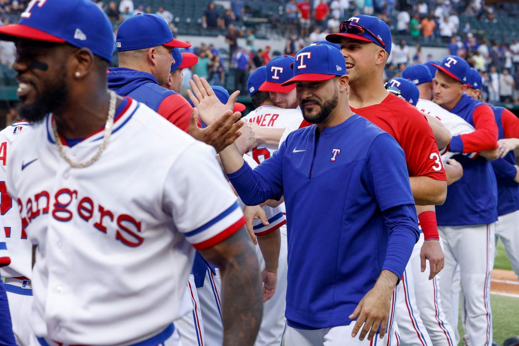 Texas Rangers starting pitcher Martin Perez (center) high-fives teammates after a game...