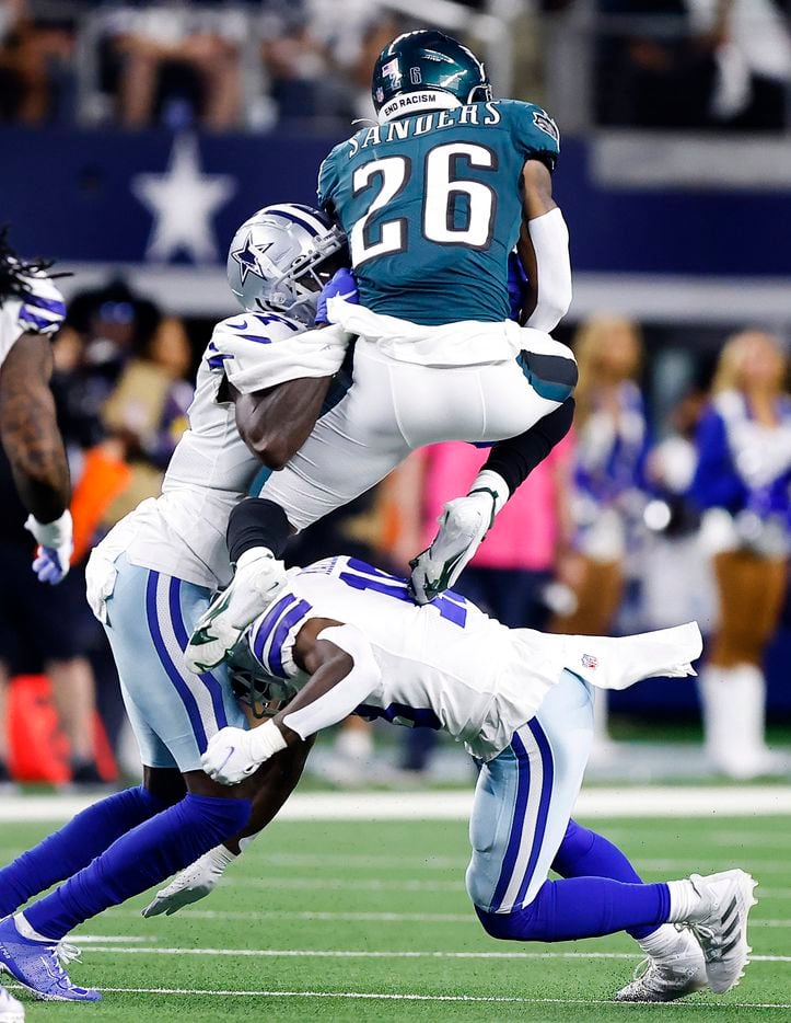 Philadelphia Eagles running back Miles Sanders (26) goes up and over Dallas Cowboys strong safety Damontae Kazee (18, bottom) and safety Jayron Kearse (27) during the second quarter at AT&T Stadium in Arlington, Monday, September 27, 2021. (Tom Fox/The Dallas Morning News)