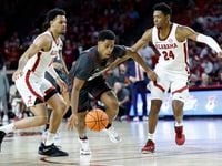 Oklahoma guard Grant Sherfield, center, dribbles between Alabama guard Dominick Welch (10)...