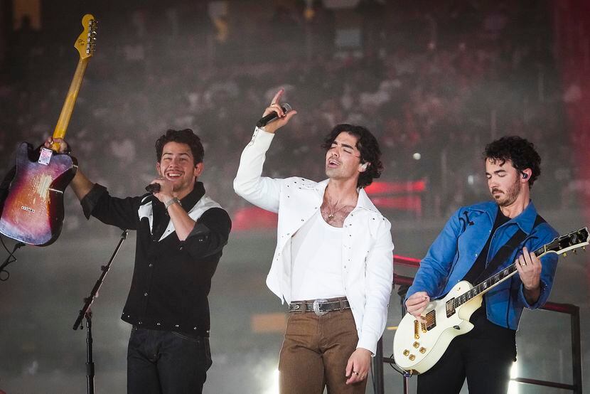 The Jonas Brothers perform with the Dallas Cowboys cheerleaders during halftime of an NFL...