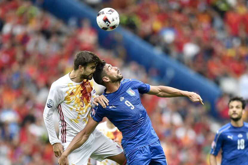 Gerard Pique de España y Graziano pelle de Italia intentan cabecear el balón en el partido...