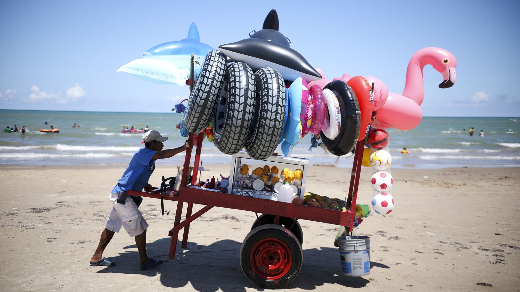Un vendedor de juguetes inflables para la playa empuja su carrito en Playa Bagdad, Tamaulipas.