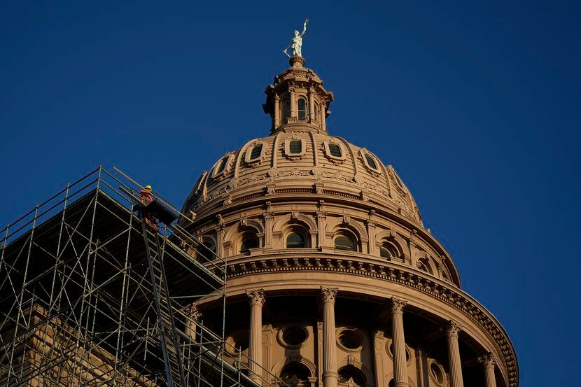 Construction workers move material for a roof restoration project at the Texas Capitol as...