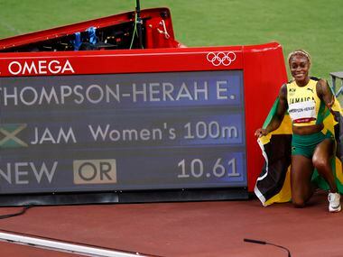 Jamaica’s Elaine Thompson-Herah holds up the Jamaican flag after winning the women’s 100...