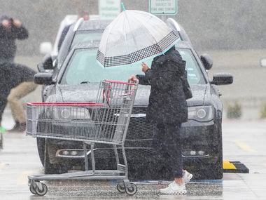 Shoppers at a Costco store in Plano navigate a cold rain in the parking lot on Monday, Jan....