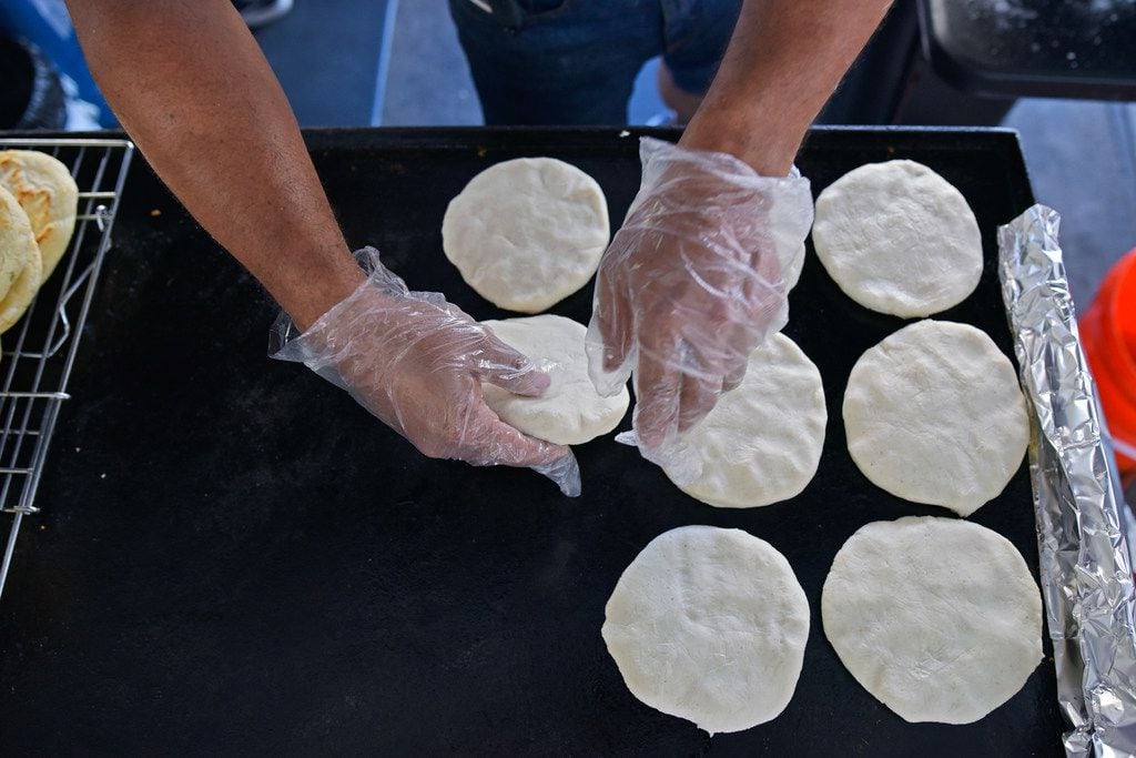 Cesar Hernandez places arepas to cook at the food booth Arepa Nation at the Dallas Farmers...