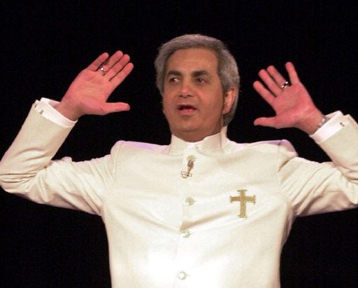 Televangelist Benny Hinn raises his hands in prayer during a service at the Blaisdell...