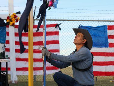 Artist Roberto Márquez places the second of six painted crosses into the ground as part of a...