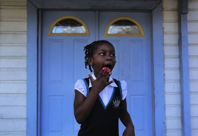 Derrionna "DeeDee" Shanks, 6, licks the last remnants of a spicy snack from her fingers following church services in West Dallas. Testing at this location showed higher than acceptable levels of lead exposure in the soil surrounding the church.
