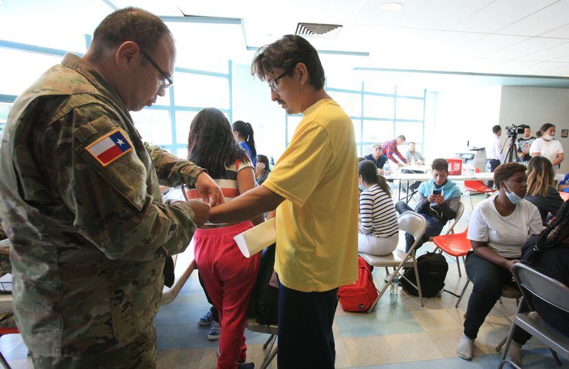 An officer from the Texas National Guard processes a migrant at Opportunity Center's Welcome...