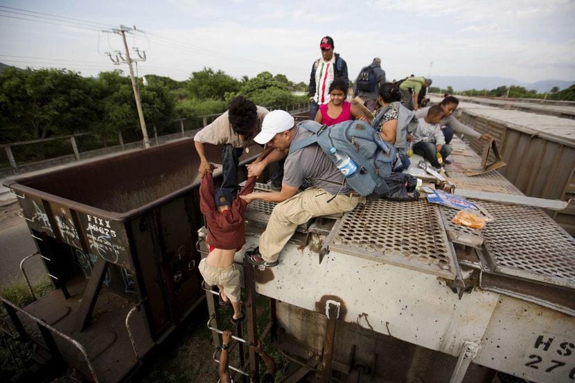 Un niño recibe ayuda para bajarse de un tren de carga en Ixtepec, Puebla. (AP/EDUARDO VERDUGO)
