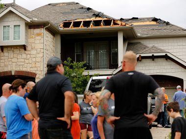 Neighbors visit outside a wind-damaged home on Oliver Dr. in North Fort Worth, after winds...