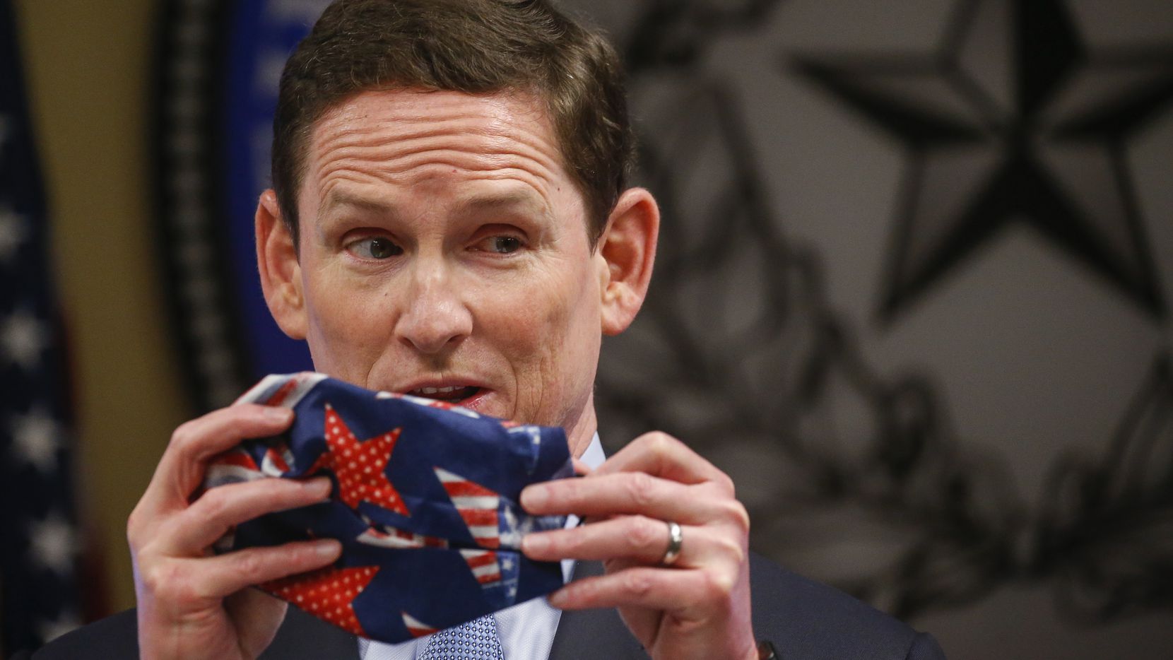 Dallas County Judge Clay Jenkins displays an improvised cloth face mask made with a bandana...
