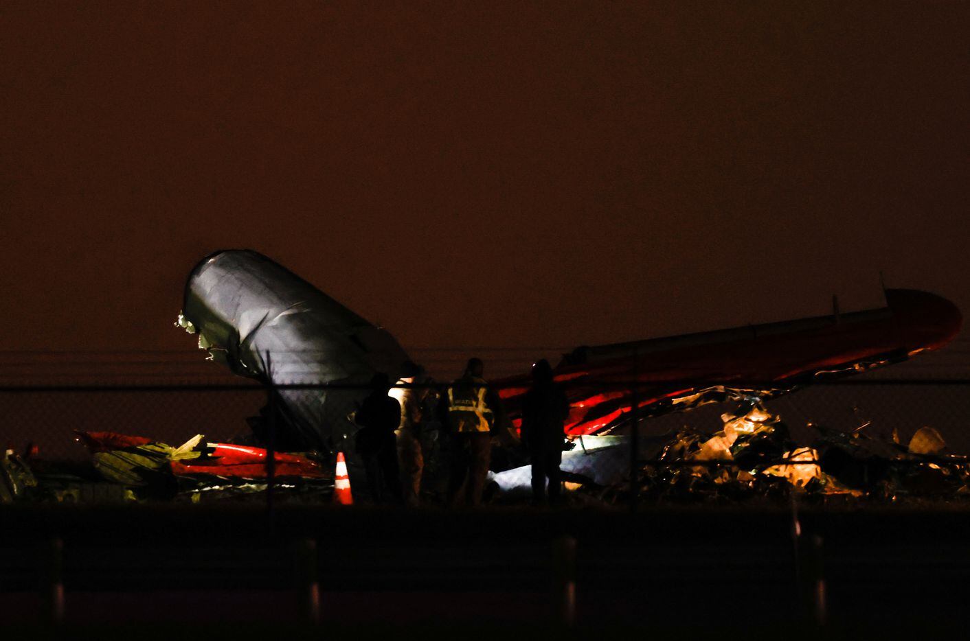 Officials point flashlights at the remains of a plane involved in a mid-air collision...