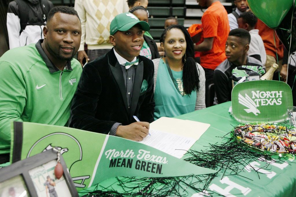 DeSoto defensive back Khairi Muhammad, 17, with his parents, signing his letter of intent to...