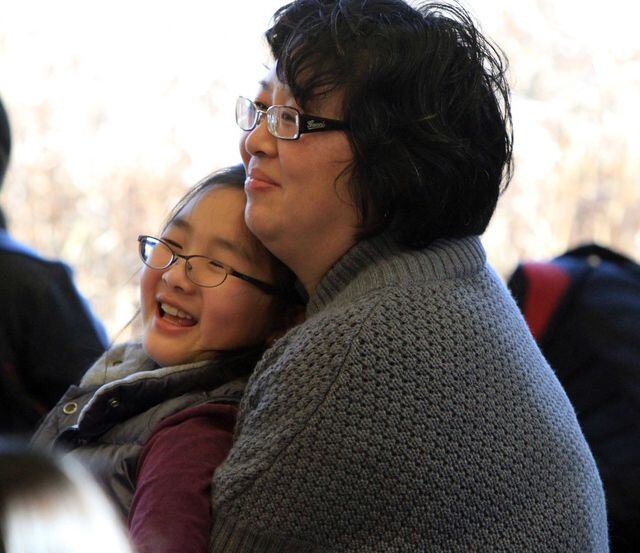 Hong Guo and her daughter enjoy a performance at the library.