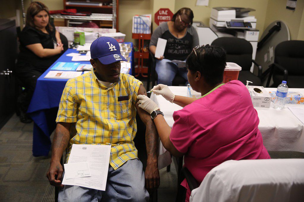 Daniel Robertson of Dallas receives the flu vaccine Tuesday from Barbara Davis at a mobile...