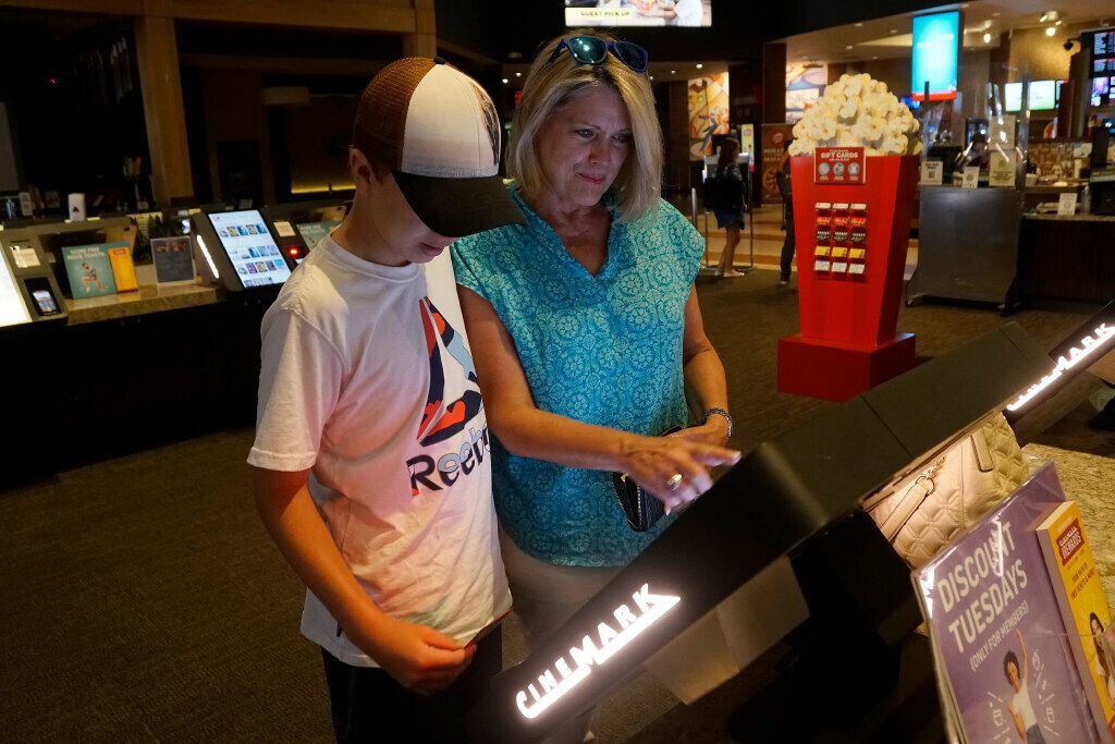 Jack Erickson (13) and his grandmother Sandy Akright purchase tickets at a kiosk at the...