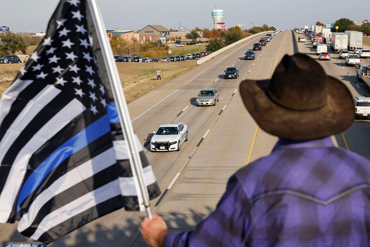 Rockwall resident Mike Tonick holds a flag during the funeral procession for Mesquite police...