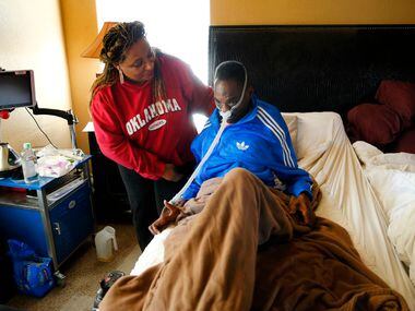 Lorraine Dixon helps her husband as he rests in bed. (Tom Fox/The Dallas Morning News)