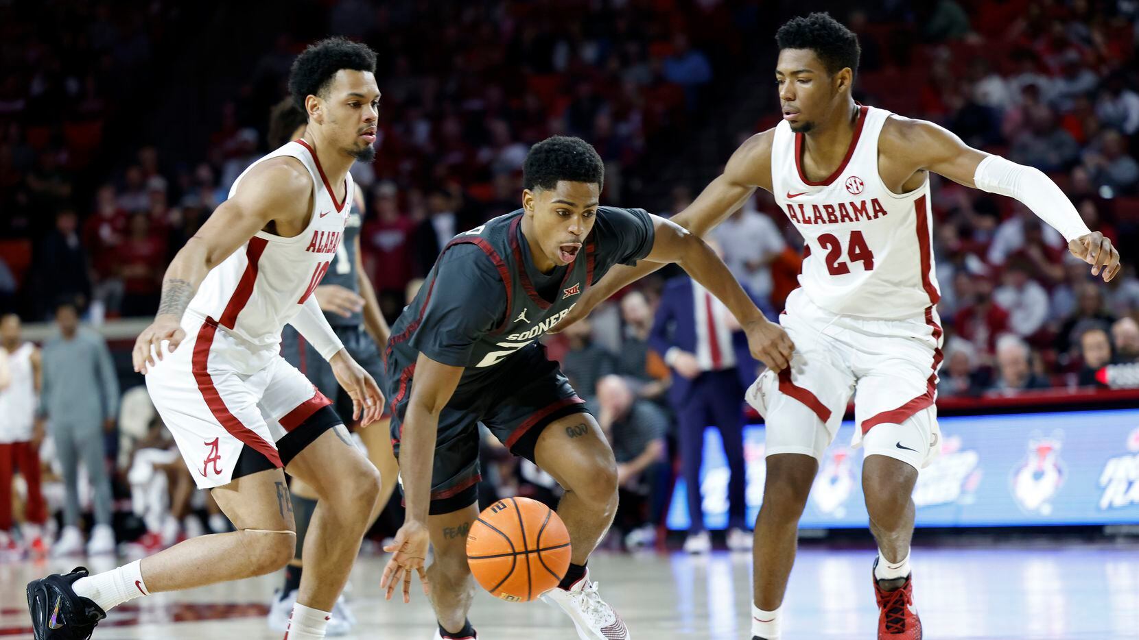 Oklahoma guard Grant Sherfield, center, dribbles between Alabama guard Dominick Welch (10)...