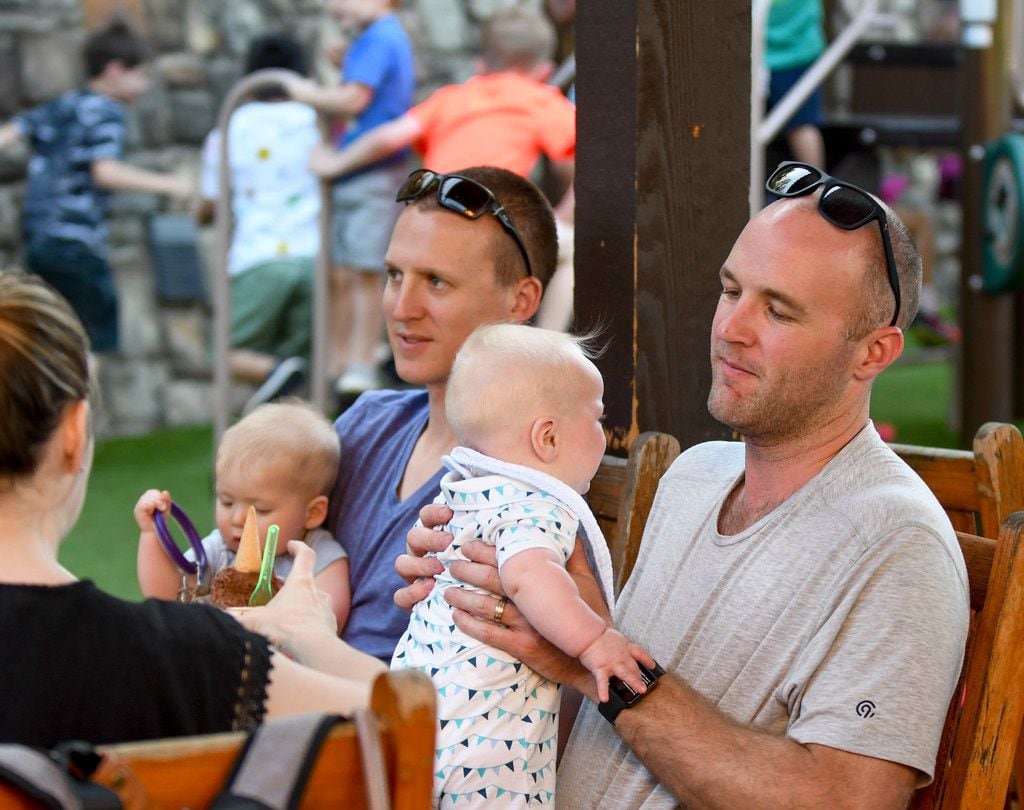 Matt Morgan, left, and Brian Wallace spend time with their sons while children play on the...