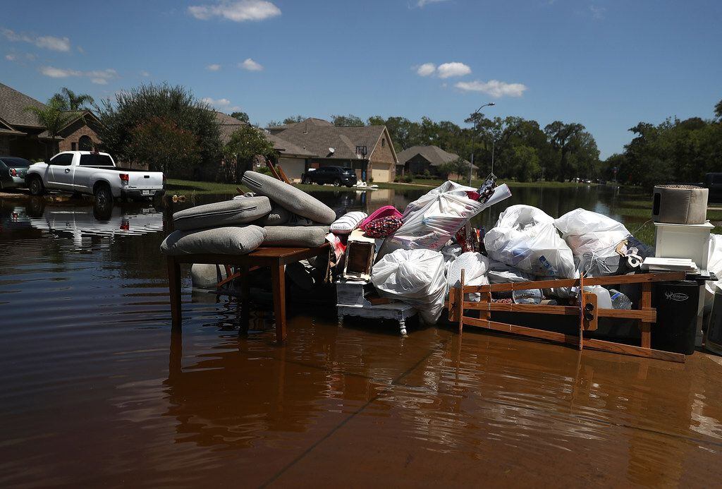 Damaged furniture and personal belongings sit in front of a flooded home Thursday in...