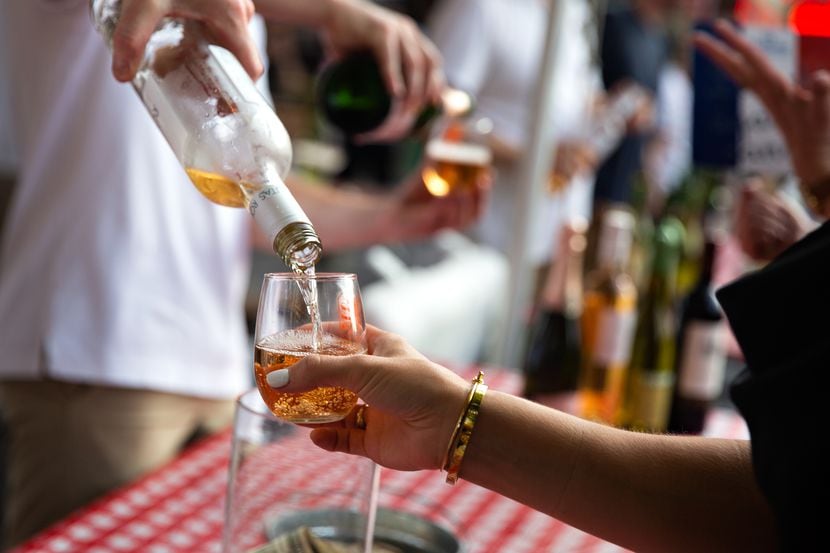Festival goers are poured varieties of wine during an outdoor festival.