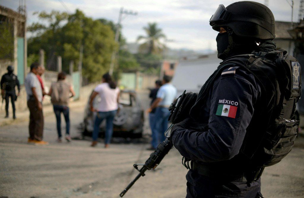 A police officer stands guard as personnel of Guerrero state attorney's office work next to...