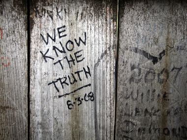 Graffiti covers the wooden fence at the top of the grassy knoll at Dealey Plaza on Saturday,...